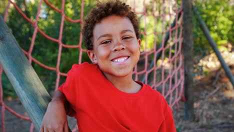 portrait of happy boy standing near net during obstacle course