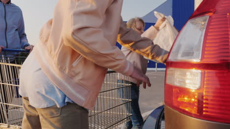 Mom-And-Daughter-Unload-Shopping-Carts-In-The-Trunk-Of-A-Car-Side-View