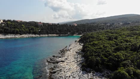 Vista-Serena-De-La-Playa-De-Emplisi-Con-La-Ciudad-De-Fiskardo-Al-Fondo-En-Kefalonia,-Islas-Jónicas,-Grecia