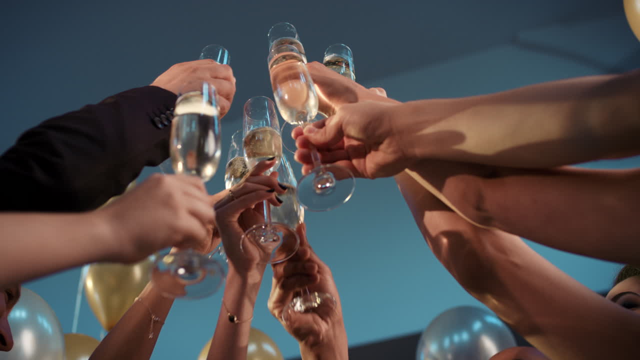 Friends holding up champagne flutes together in a toast at party