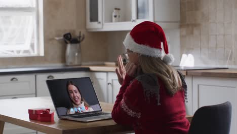 Caucasian-woman-wearing-santa-hat-on-laptop-video-call-during-christmas-at-home