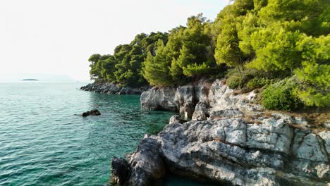 a rocky coastline with turquoise water and lush pine trees in a serene coastal landscape