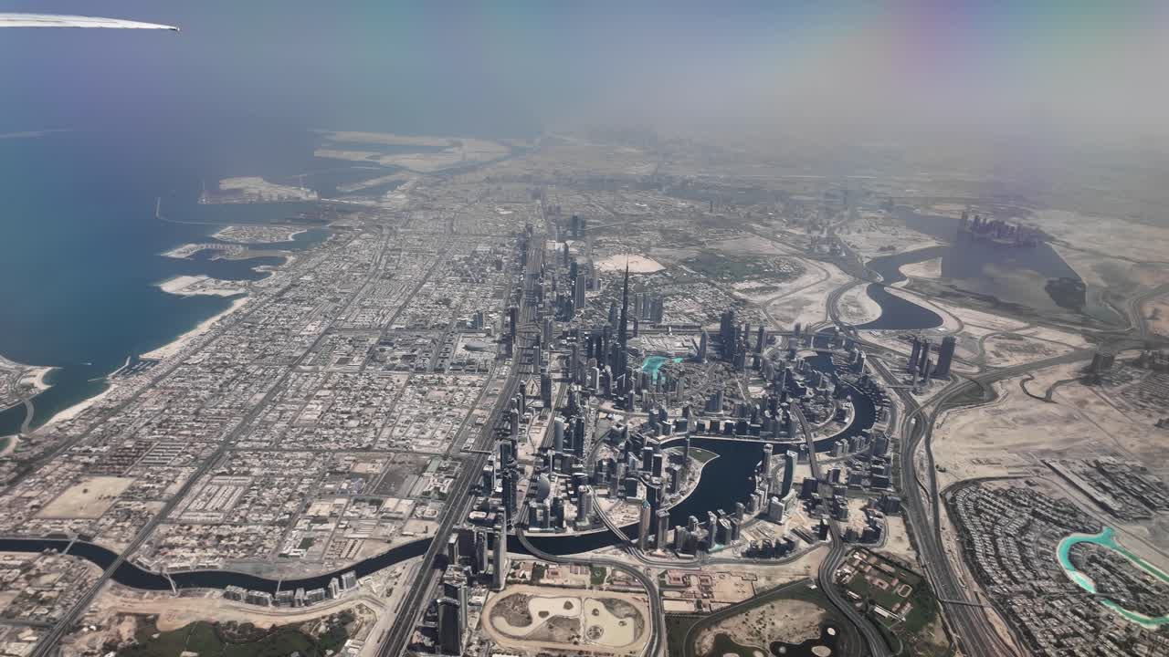 Aerial view of Dubai's iconic cityscape and coastline captured from an airplane. Skyscrapers dominate the scene showcasing Dubai's architectural marvels.