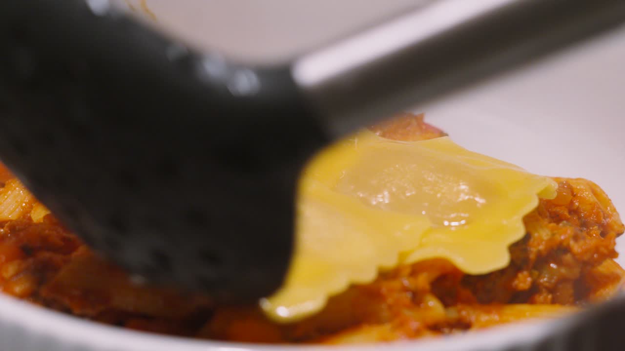 Ravioli Being Placed on Penne Bolognese Pasta. Small Parcels Filled with Meat and Vegetables. Italian Traditional Food Cuisine.