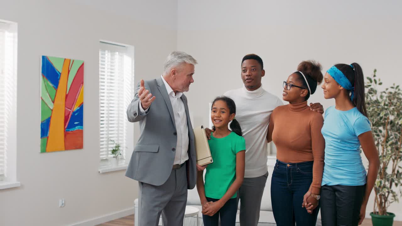 agente inmobiliario maduro experimentado guía a la familia a través de apartamentos para venta, para alquilar, señala habitaciones, presenta las ventajas de apartamentos