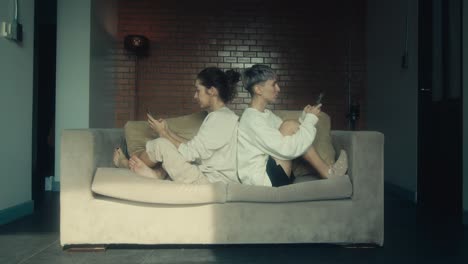 Two Women Relaxing on a Sofa with Mobile Phones