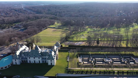 an aerial view over an upscale, luxury mansion with an eight reflection pool fountain, on long island