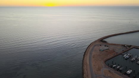 Drone-aerial-panning-up-over-Exmouth-harbour-with-sun-peaking-through-dawn