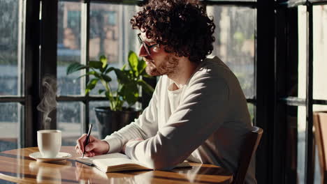 man writing in a cafe