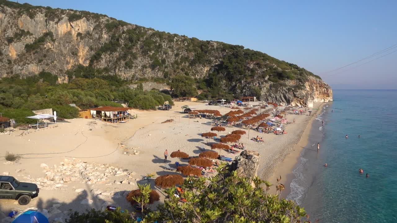 Slow motion pan over famous Gipje beach in Southern Albania with umbrellas