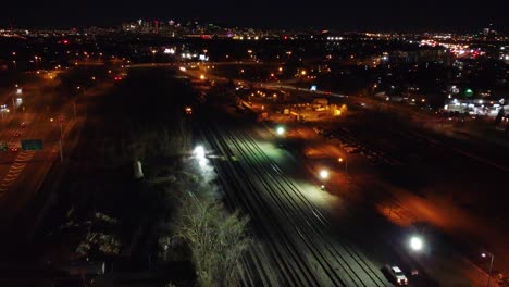 accidente de tren por la noche, por la noche en la oscuridad, tren al lado de las vías del tren, rescate, emergencia, accidente, disparo panorámico, paisaje urbano por la noite, tráfico en la carretera en el fondo