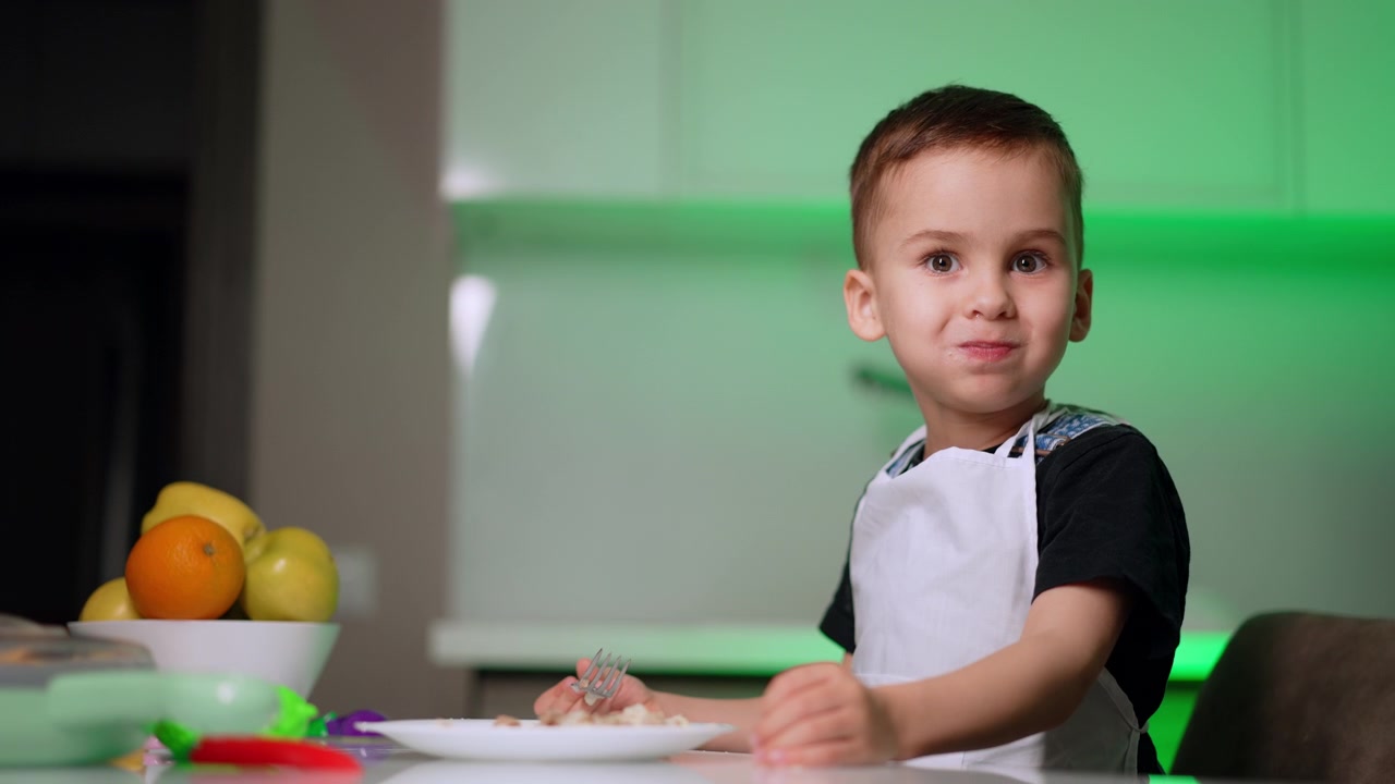 Niño pequeño haciendo una mueca mientras desayuna en la cocina