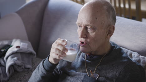 elderly man drinking milk on couch