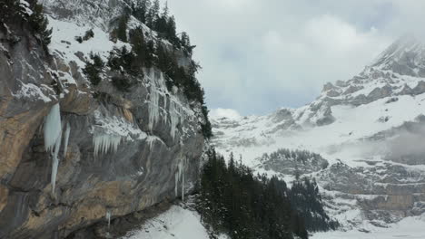 aerial dolly from ice covered mountain wall to beautiful snow covered valley