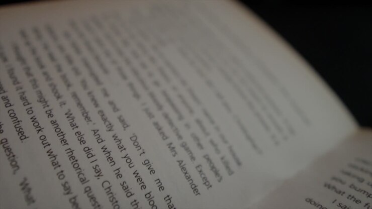 A close up cinematic shot dollying diagonally across the printed text on the pages of an interesting novel in a studio