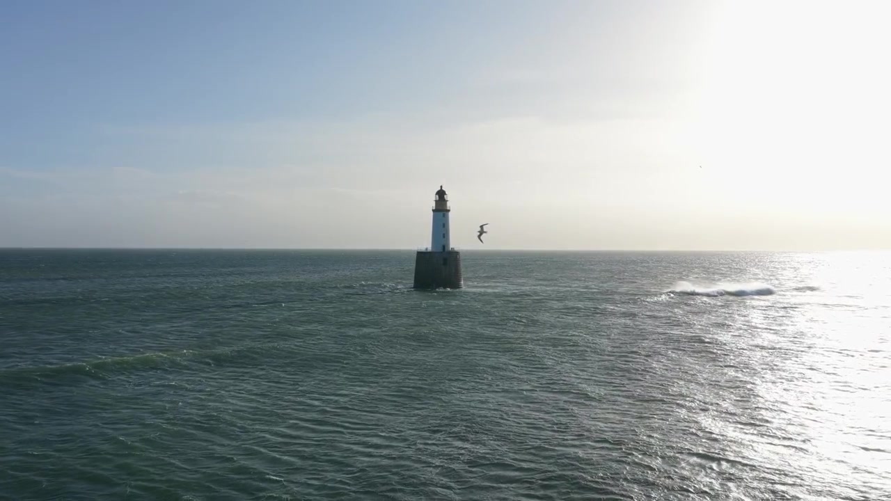 Riprese con drone che si allontanano da una spiaggia sabbiosa sul Mare del Nord verso lo storico faro di Rattray Head nell'Aberdeenshire, Scozia.