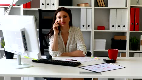 mujer de negocios sentada en una silla de oficina hablando por teléfono