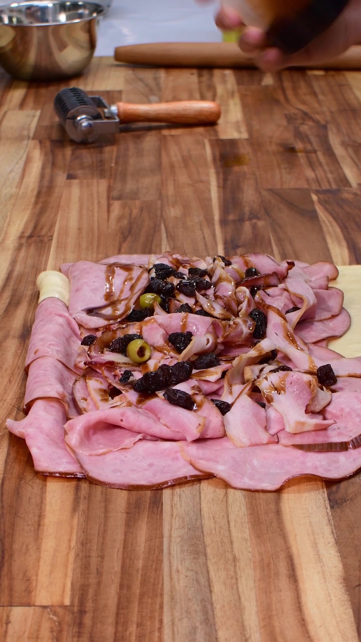 Versando sciroppo dolce di papelon su prosciutto e uvetta per il tradizionale pan de jamon.