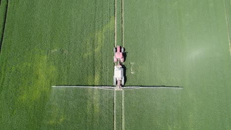 Luftaufnahme-Von-Oben-Nach-Unten-Des-Landwirtschaftlichen-Sprühgeräts,-Das-Im-Frühjahr-Insektizide-Auf-Die-Landwirtschaftlichen-Arbeiten-Auf-Der-Grünen-Wiese-Sprüht
