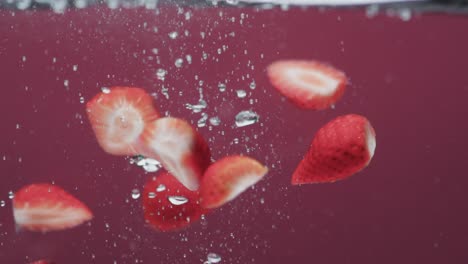 Video-Von-Erdbeeren,-Die-Ins-Wasser-Fallen,-Mit-Kopierraum-Auf-Rotem-Hintergrund