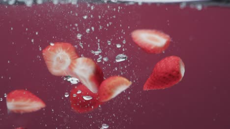 video of strawberries falling into water with copy space on red background