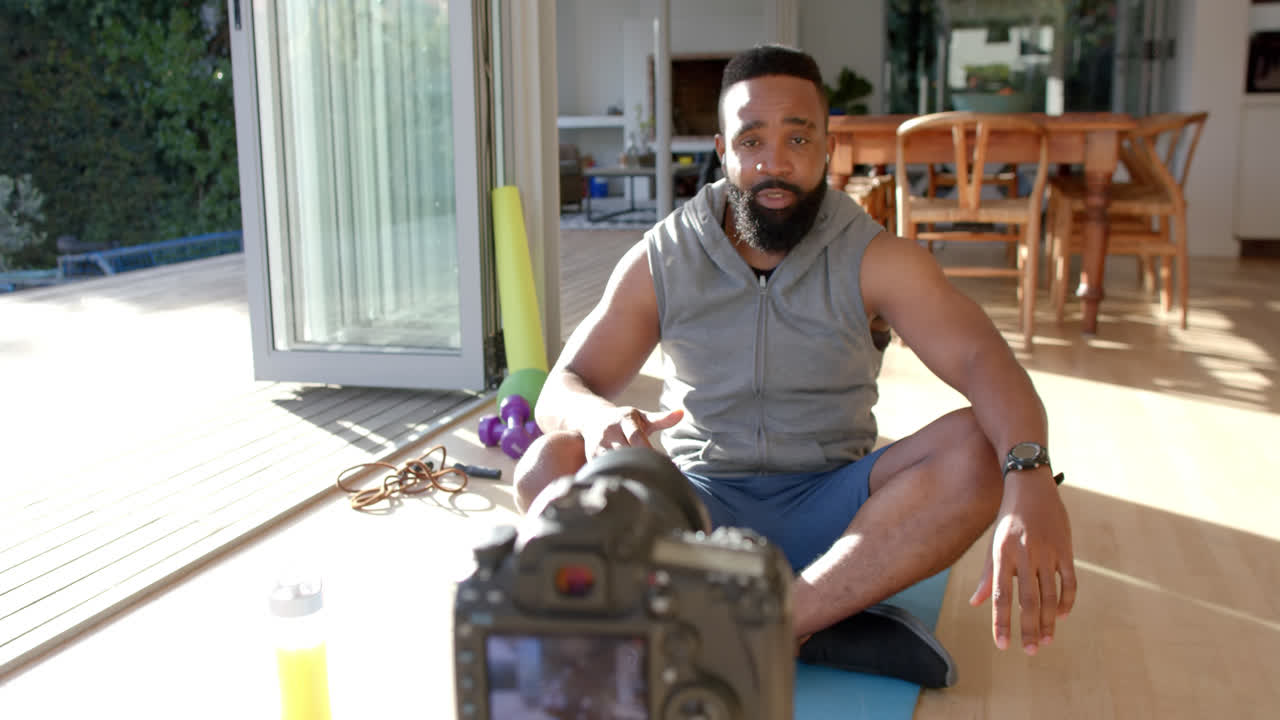 African american male fitness vlogger advicing and filming at home, slow motion