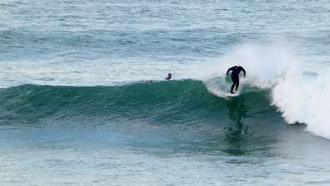 surfer with white helmet catching wave in beach and doing a great carver