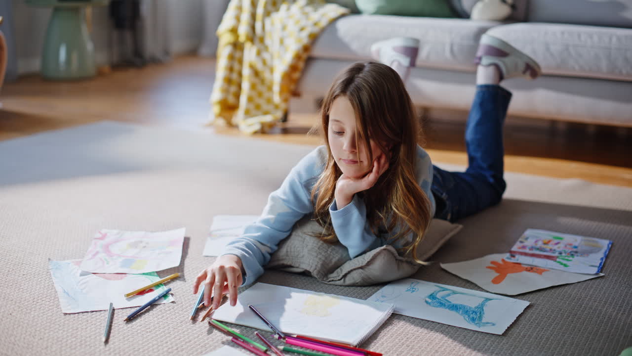 Bambina di talento che disegna da vicino sul pavimento di casa. Ragazza impegnata in un hobby creativo