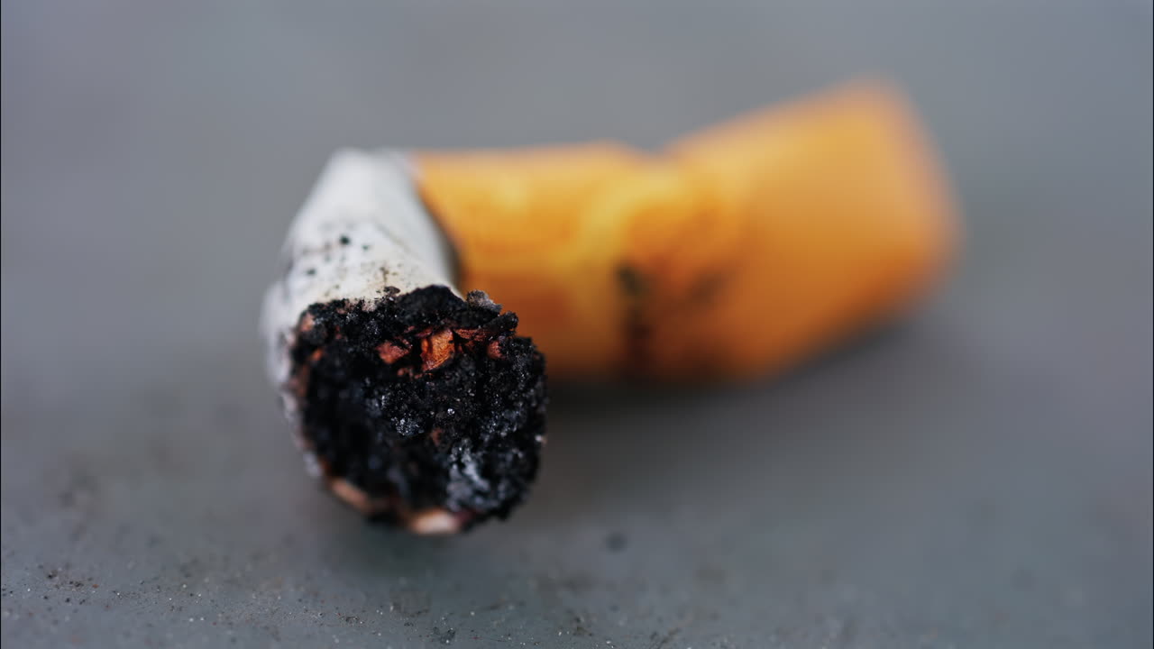 Close up of a smashed cigarette butt on a grey surface