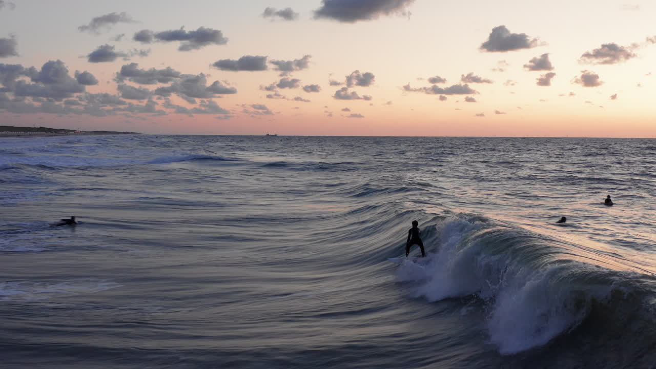 surfistas frente a la ciudad turística domburg en los países bajos durante la puesta de sol