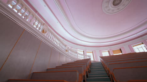 empty auditorium at university. large classroom with rows of wooden desks without students. steps among tables in the large lecture hall. pandemic.