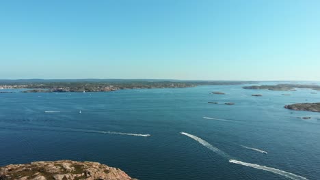 speedboats crossing each other on the ocean in sweden on a clear summer sky - aerial shot