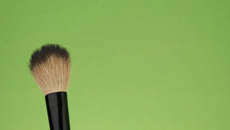 horizontal movement of the brush for makeup on a green background.