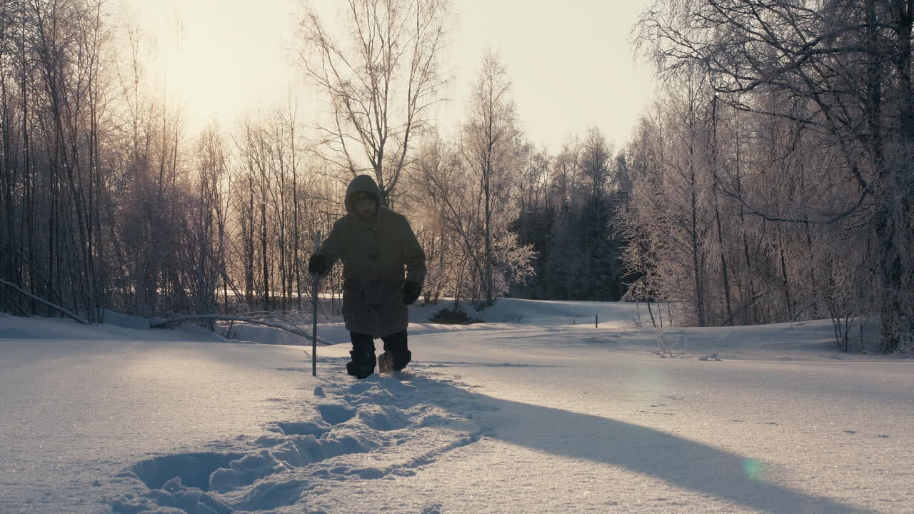 hombre vestido de invierno camina en nieve profunda y crujiente en un bosque congelado de frío extremo