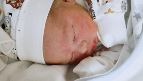 beautiful newborn baby face in a cap. caucasian child lies his head to camera. close up.