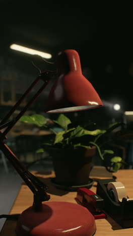 red desk lamp on wooden desk with plant