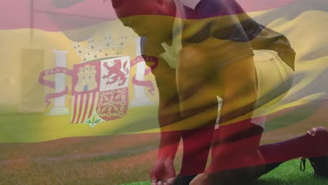 Animation-Einer-Spanischen-Flagge,-Die-über-Einem-Männlichen-Rugbyspieler-Gemischter-Abstammung-Weht,-Der-Auf-Einem-Spielfeld-Kniet