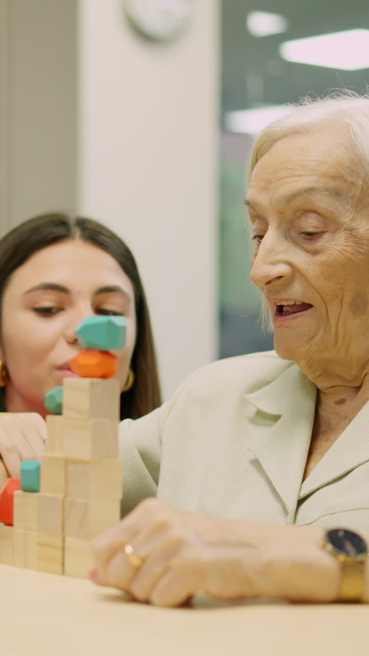 Elderly woman and young woman playing with wooden blocks
