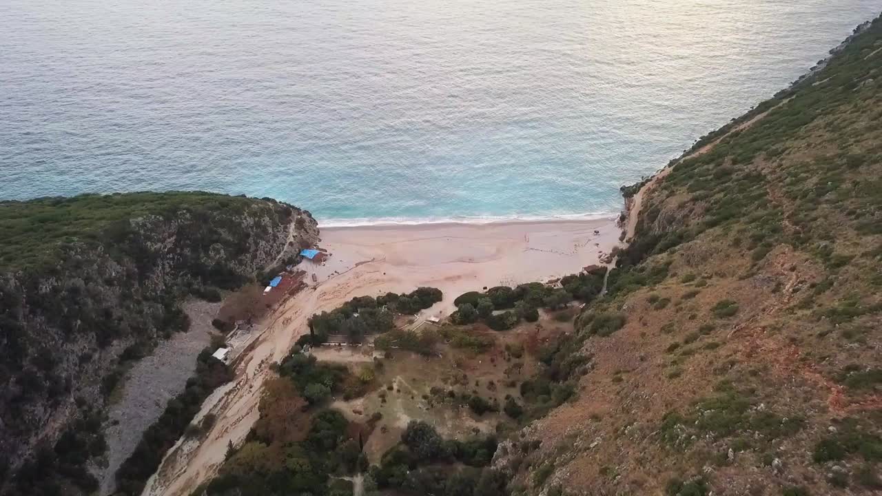 Gjipe Beach at sunset along the Albania Riviera with beach huts and the waves crashing in on the beach
