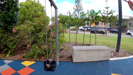 side view of a young boy swinging high at a colourful new playground