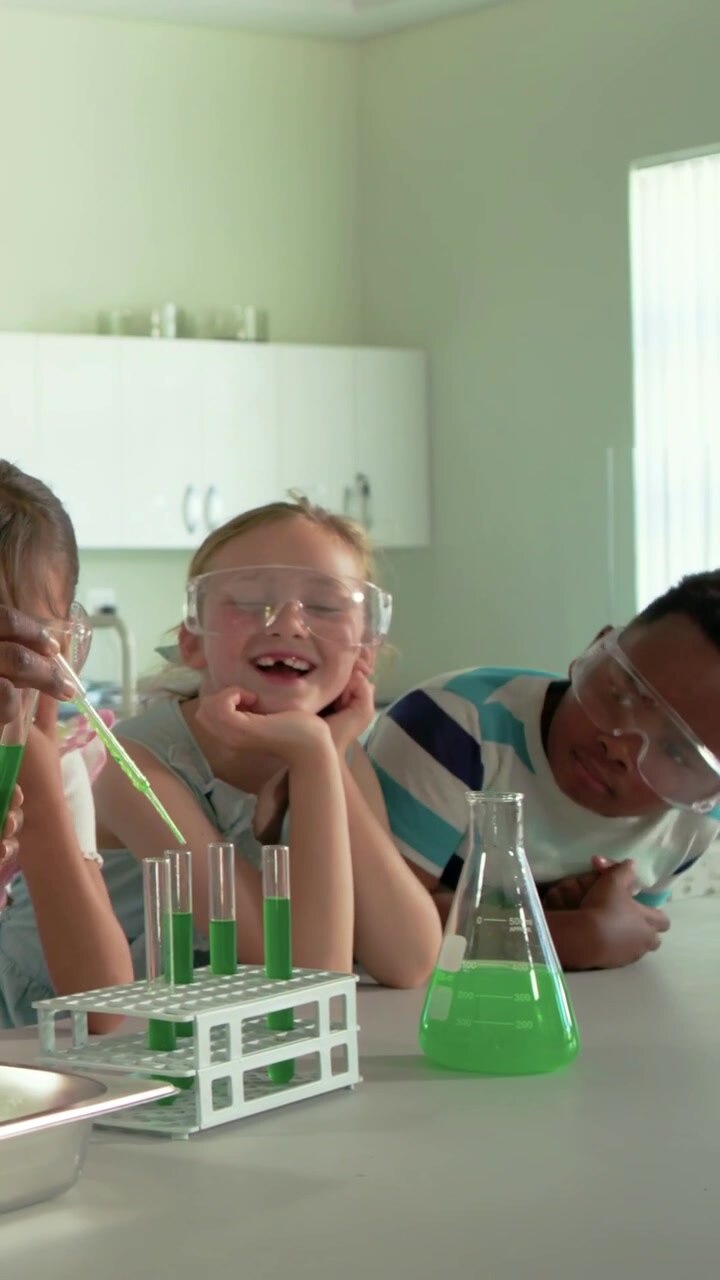 Vertical video: Using pipette, student adding green liquid into tubes at school to observe reaction