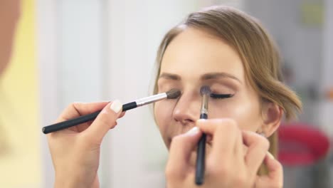 vista de cerca del artista de maquillaje aplicando sombra de ojos en el párpado usando un pincel de maquillaje. maquillaje profesional. toma en cámara lenta