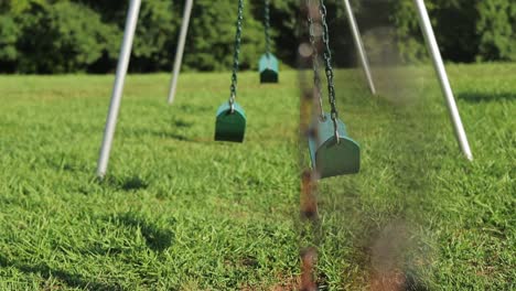 swings in playground set swinging back and forth slow motion shallow depth of field