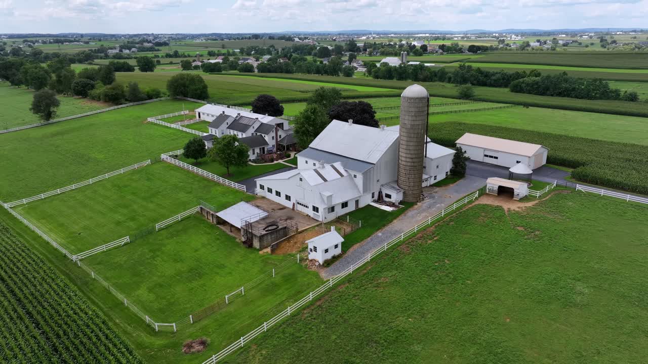 Beautiful large farmstead with house,barn, stable and silos in agricultural fields during cloudy day in summer