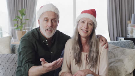 una pareja caucásica de mediana edad con sombreros de papá noel en ideo charla en navidad en casa, en cámara lenta