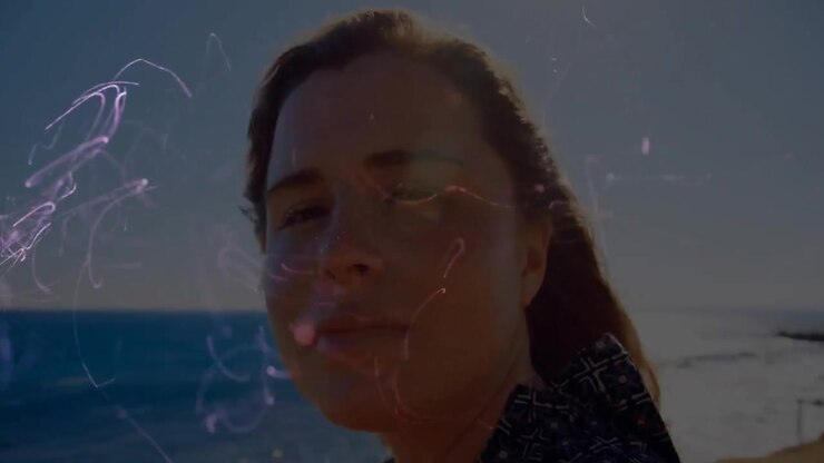 Woman Drinking from Bottle with Abstract Glowing Light Particles by the Ocean