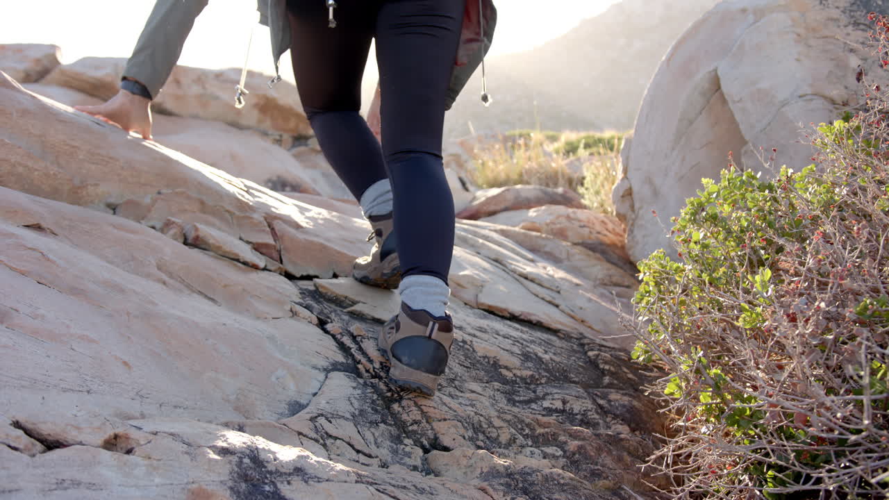 Hiking up rocky terrain, woman wearing boots and leggings on mountain trail