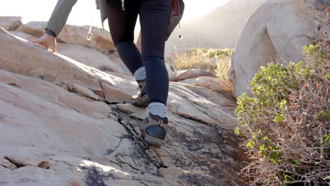 hiking up rocky terrain, woman wearing boots and leggings on mountain trail