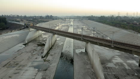 light rail train crossing a bridge over the la river concrete channel