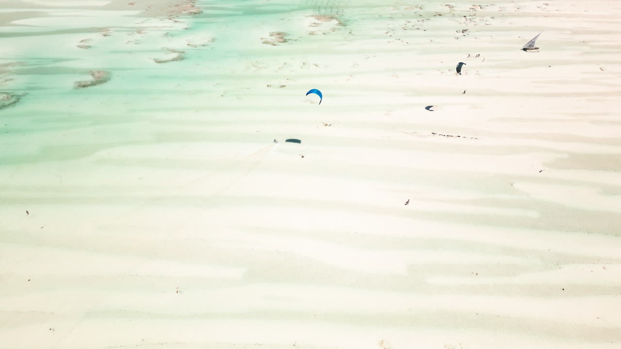 키트 서퍼 는 세일 보트 근처 의 투르코이즈 물 위 에 글라이드 하고 있다